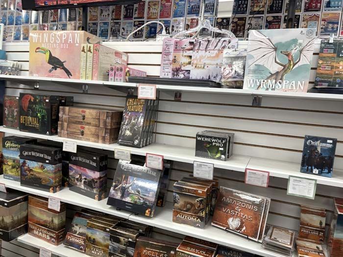 Shelves stocked with board games in a store. Various box designs and sizes.