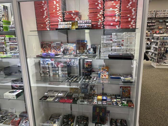 A glass display case in a game store filled with various video games.
