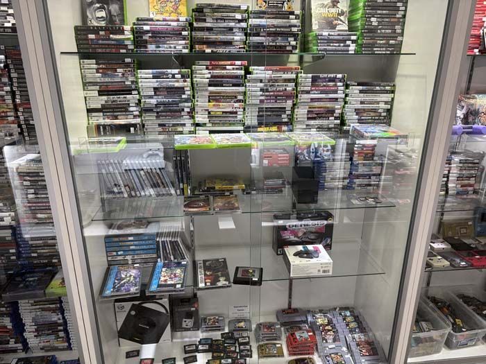 Glass display case filled with video games and accessories in a store.