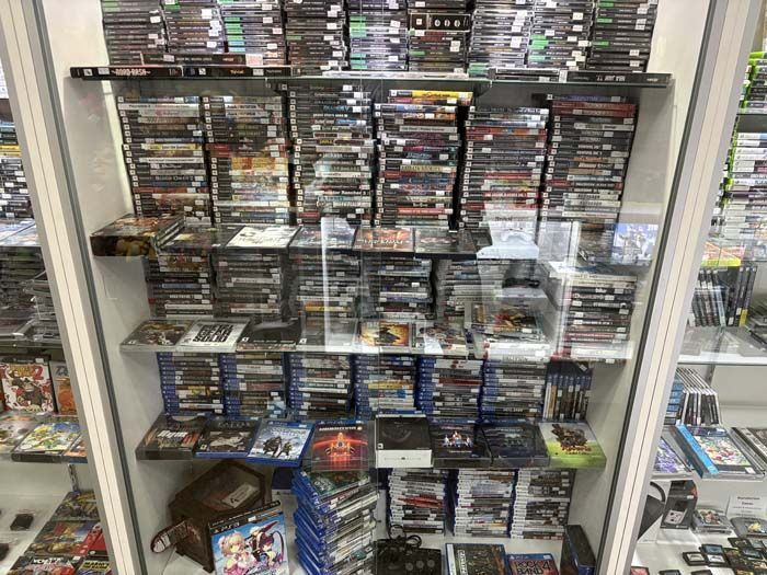 Display case filled with video game cases for sale, in a store setting.
