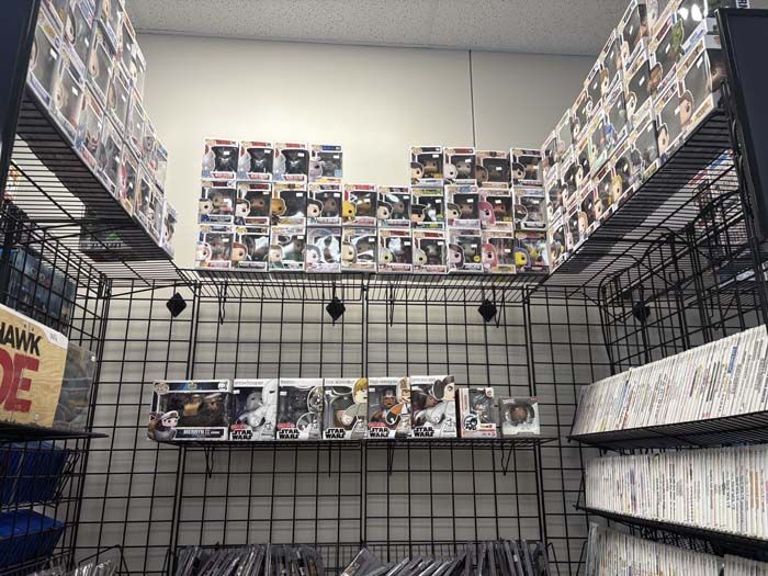 Shelves displaying a variety of Funko Pop figures in a store, with some visible comic books.