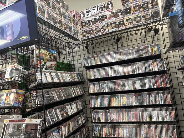 A store with a wall of DVDs and Funko Pops.