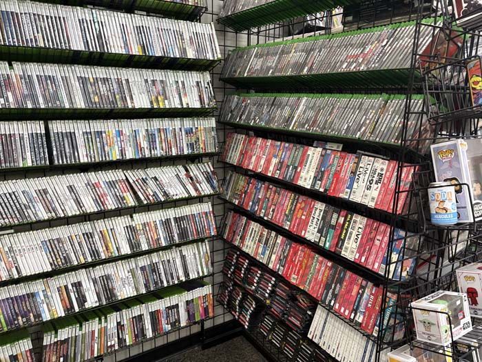 Shelves packed with video games in a store, displaying various game cases.