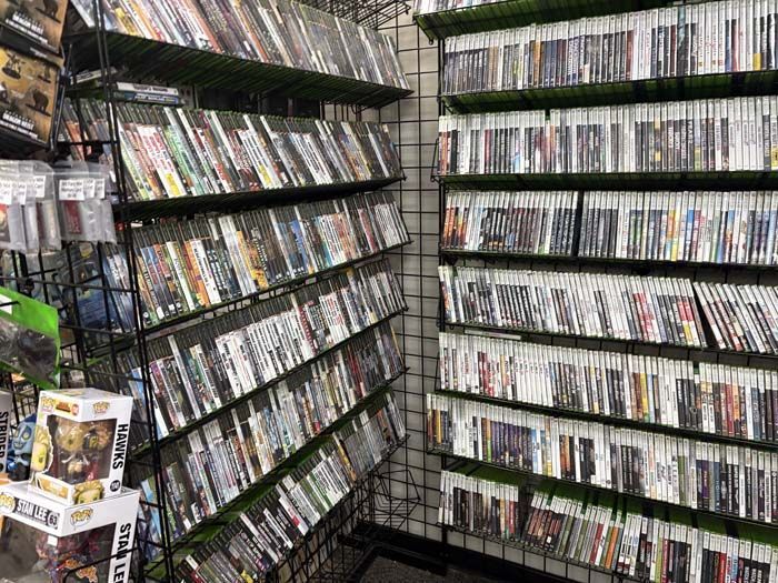 Shelves packed with video game cases in a store, displaying various game titles.