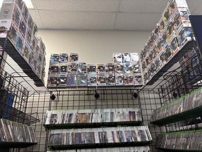 Shelves of video games and action figures in a store.