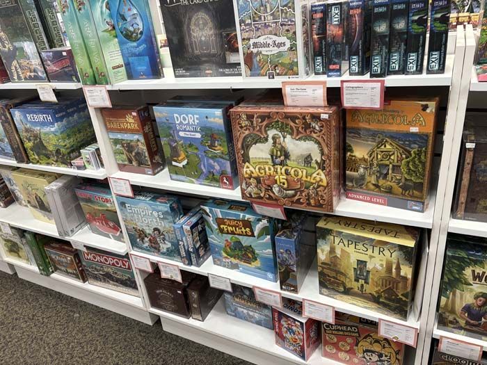 Shelves of board games in a store; boxes with colorful art, price tags visible.