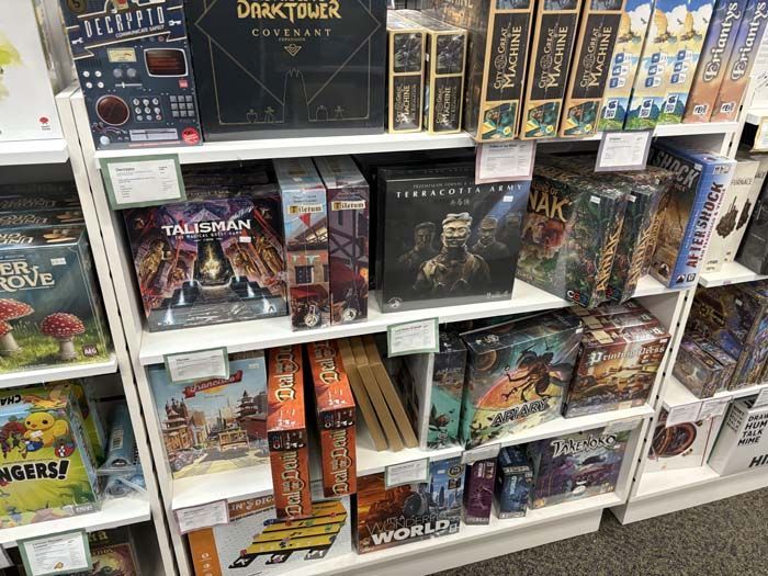 Shelves displaying board games for sale in a store, including Talisman and Dark Tower.