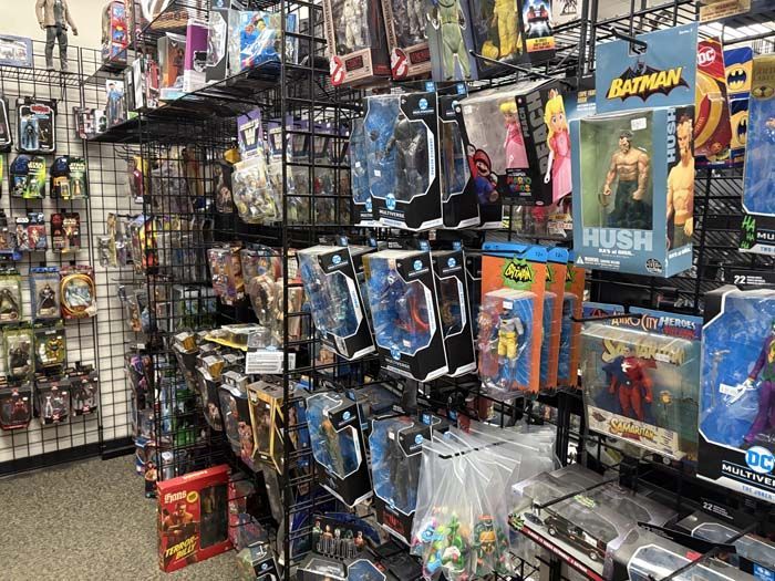 Action figures on display shelves in a store. Mostly superhero and comic book characters in packaging.