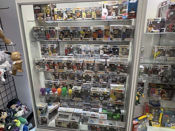 Display case filled with collectible figurines, mostly Funko Pops, in a store.