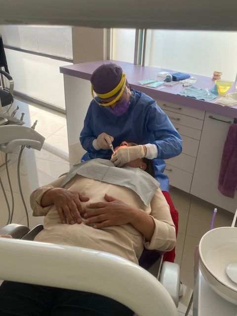 Dentista con equipo de protección trabajando en la boca de un paciente en un consultorio dental.