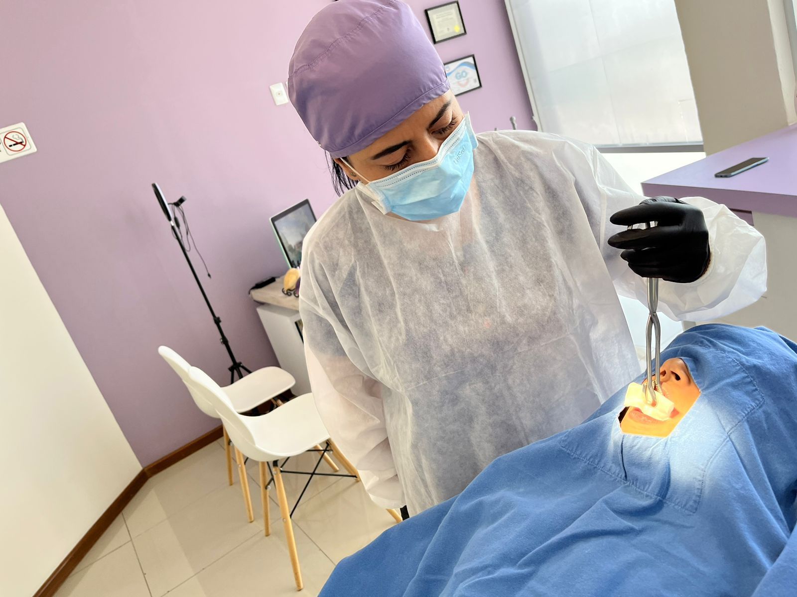 Dentista con equipo de protección realizando un procedimiento en un paciente en un consultorio médico.