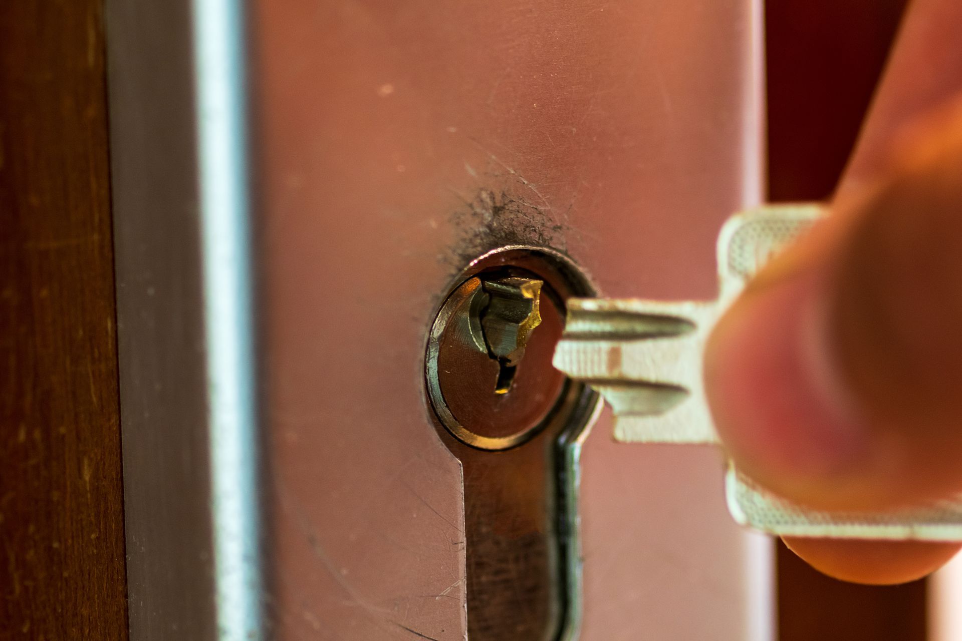A key being inserted into a lock on a wooden door, close-up.
