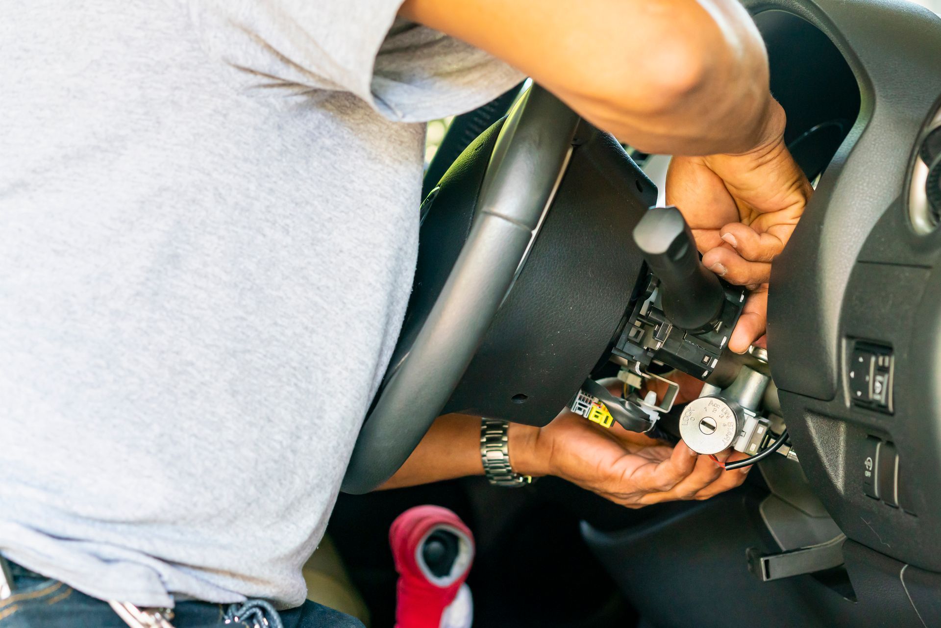 Person working on a car's steering column, likely installing or repairing the ignition system.