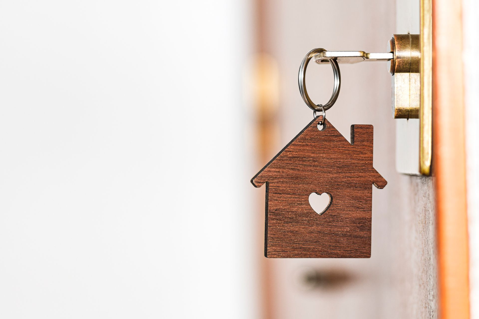 Key in door with wooden house-shaped keychain.