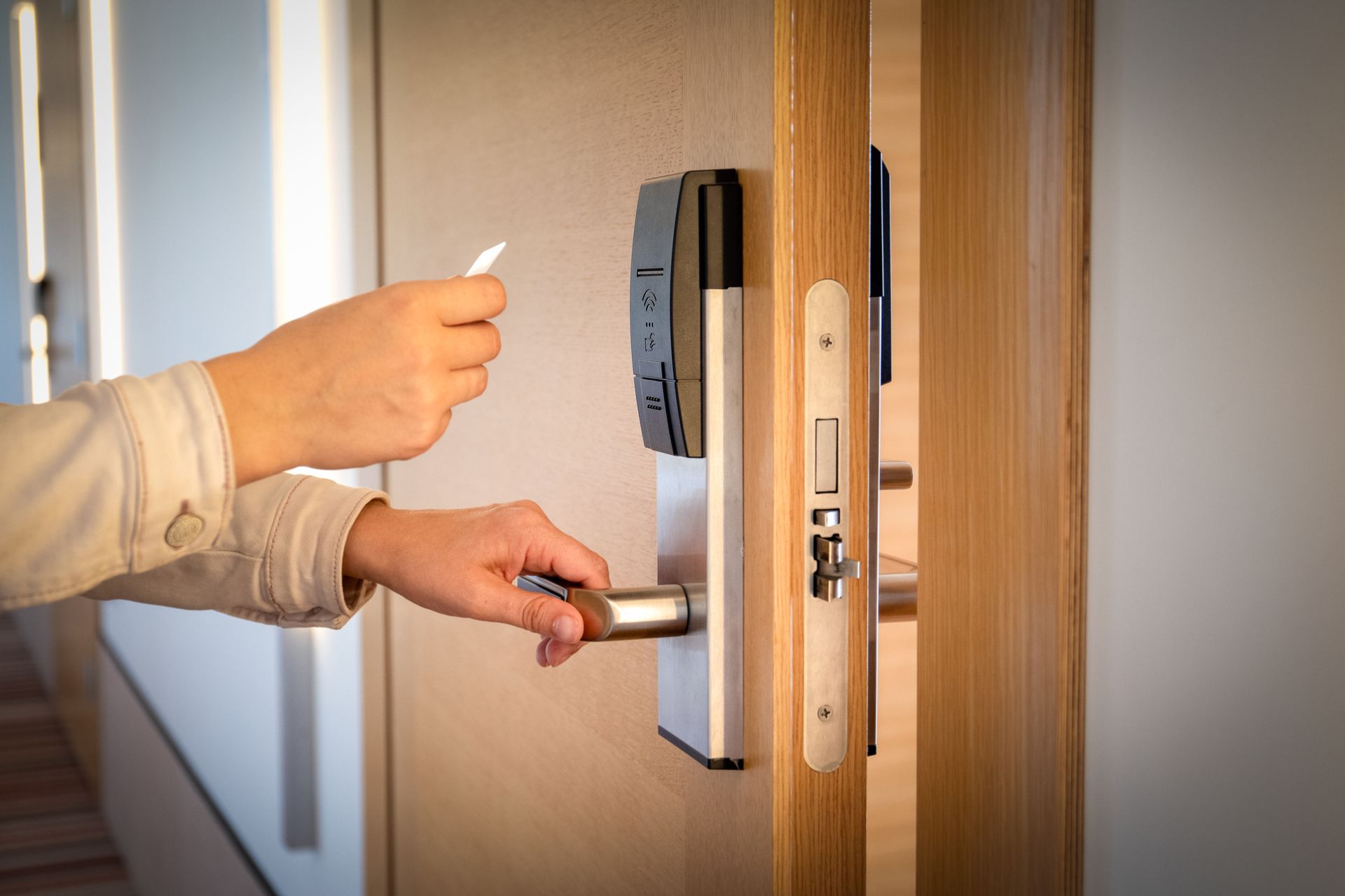 Person using a key card to unlock a hotel room door.