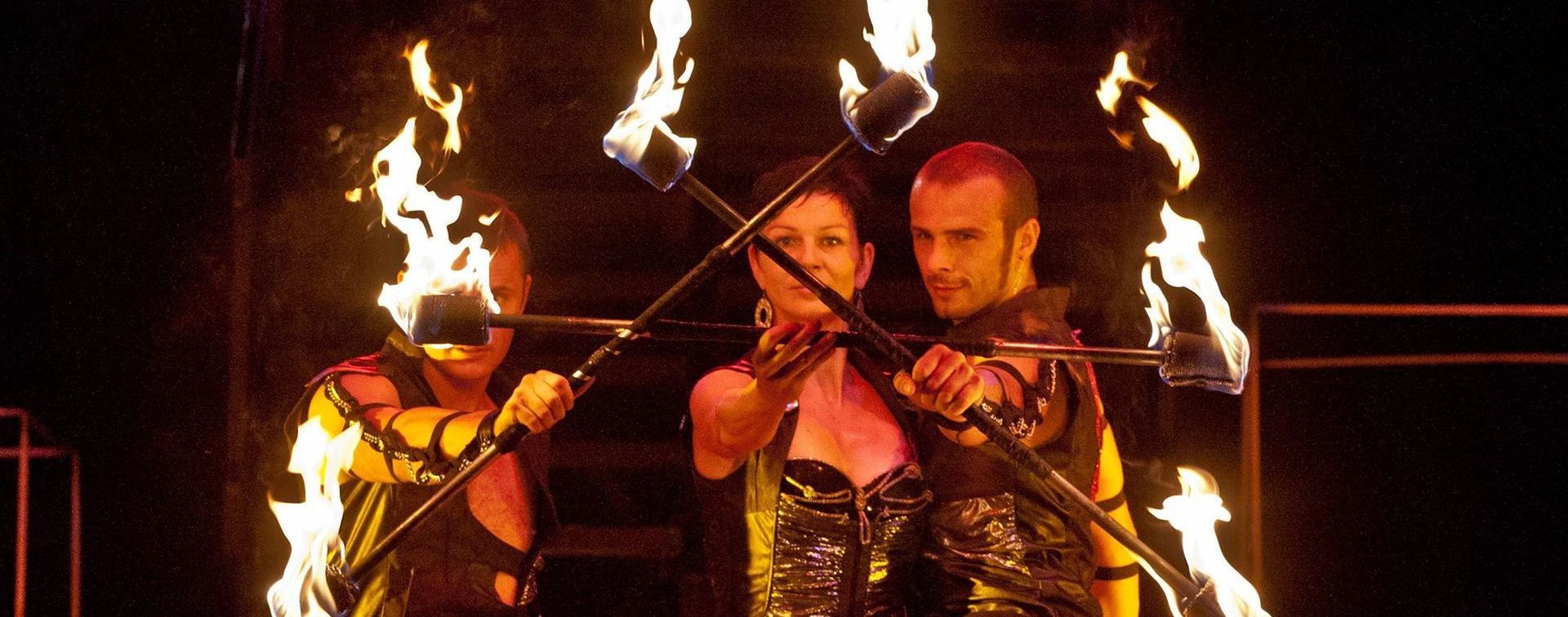 Un gruppo di persone suona dei violini dai quali esce del fuoco.