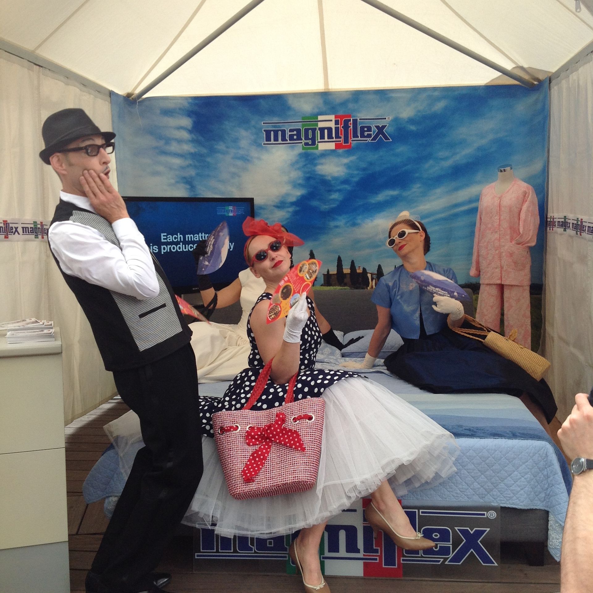 Un gruppo di persone in piedi davanti a un cartello che dice magniflex