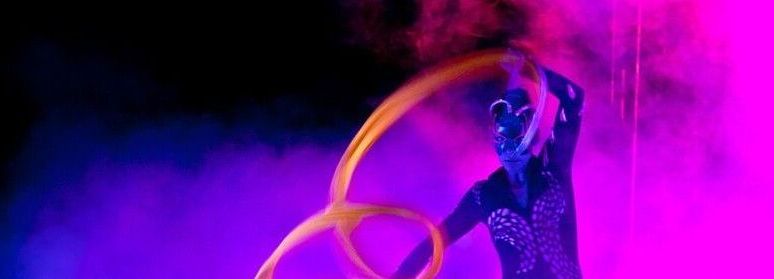 Una donna tiene in mano un cerchio di hula hoop davanti a uno sfondo viola.