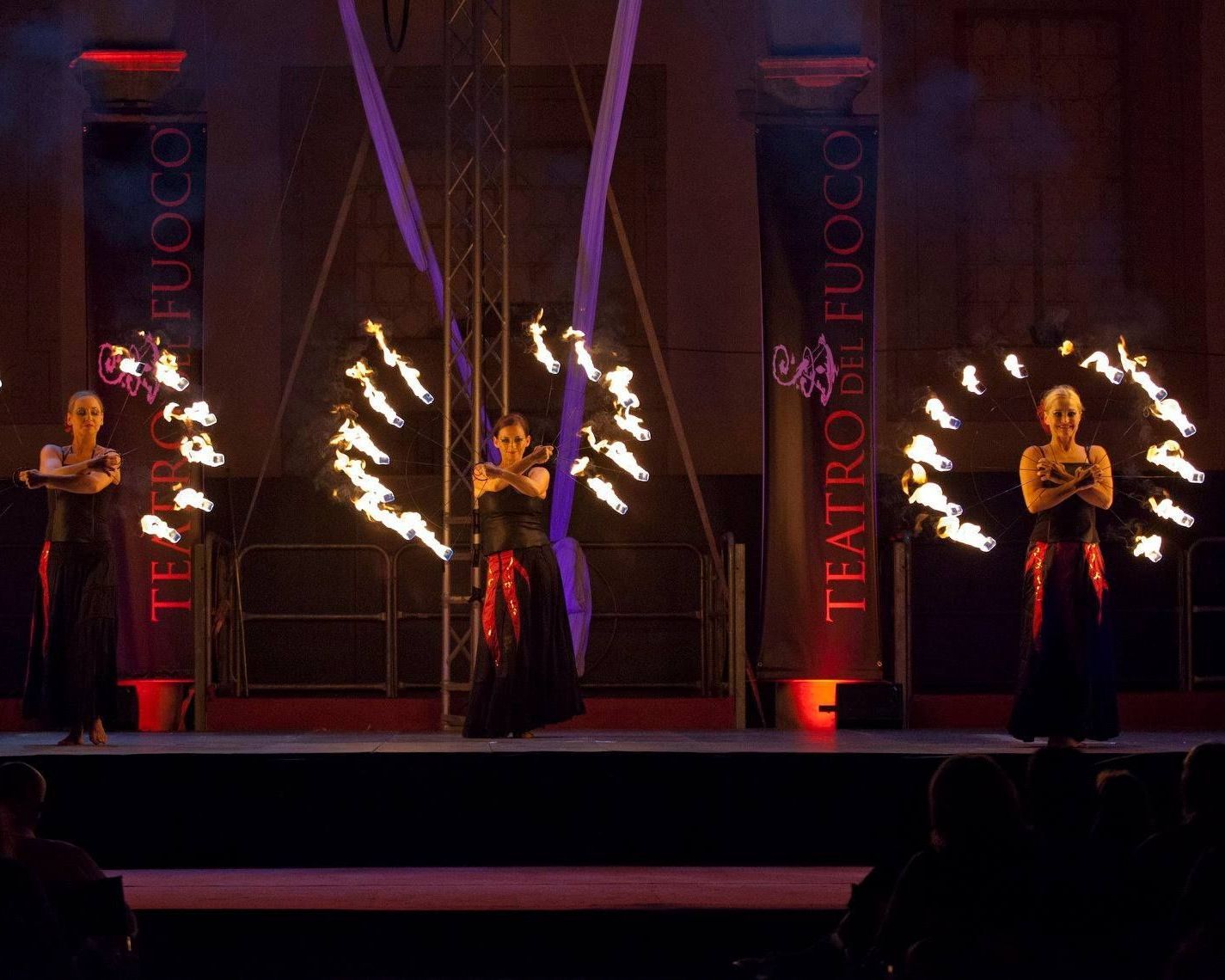 Un gruppo di donne si esibisce su un palco davanti a un cartello che dice 