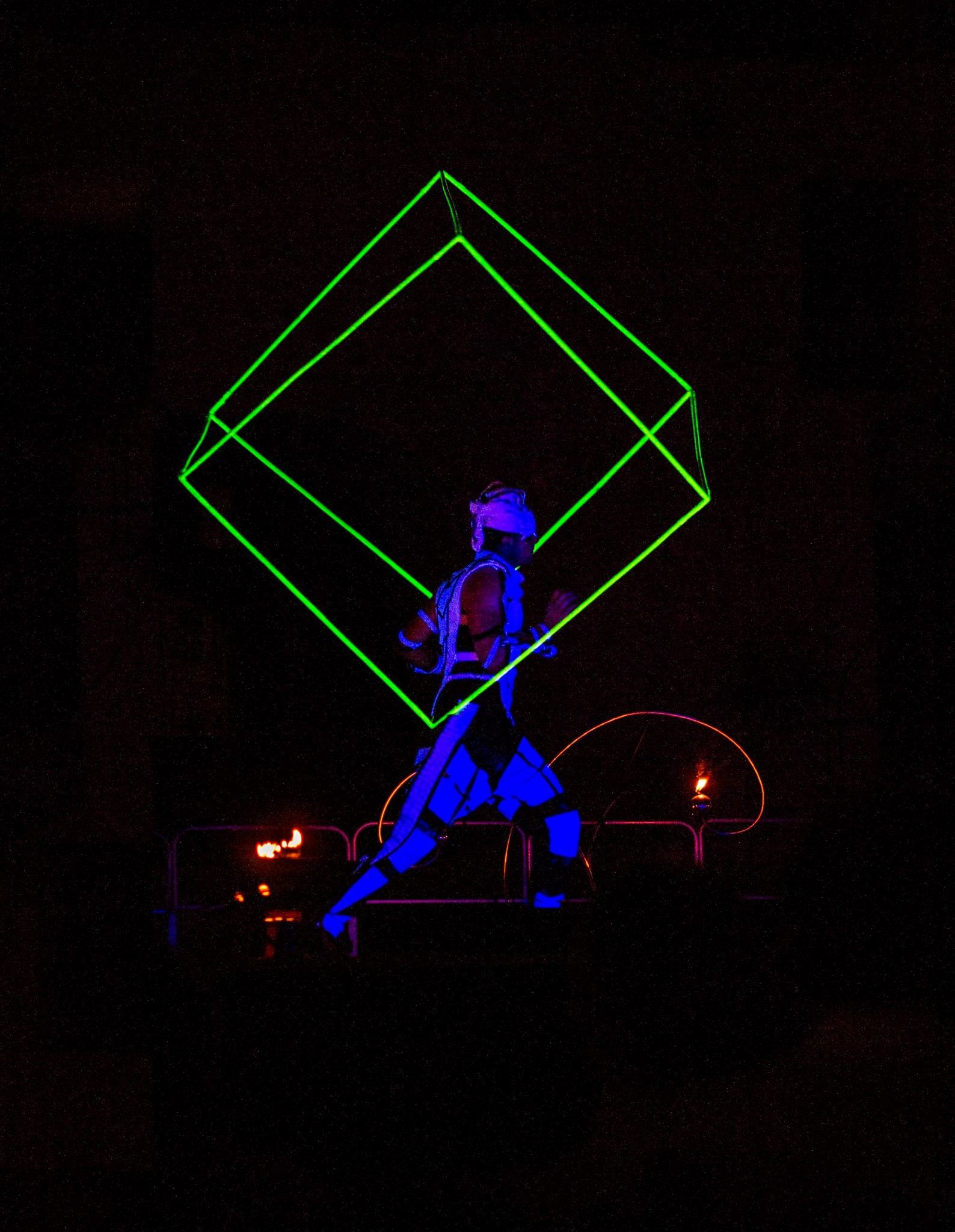 Una persona è in piedi davanti a un cubo luminoso al buio