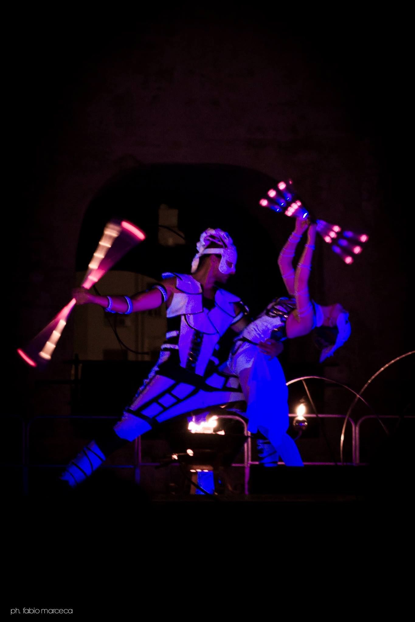 Un uomo e una donna stanno facendo i giocolieri con dei bastoncini fosforescenti.