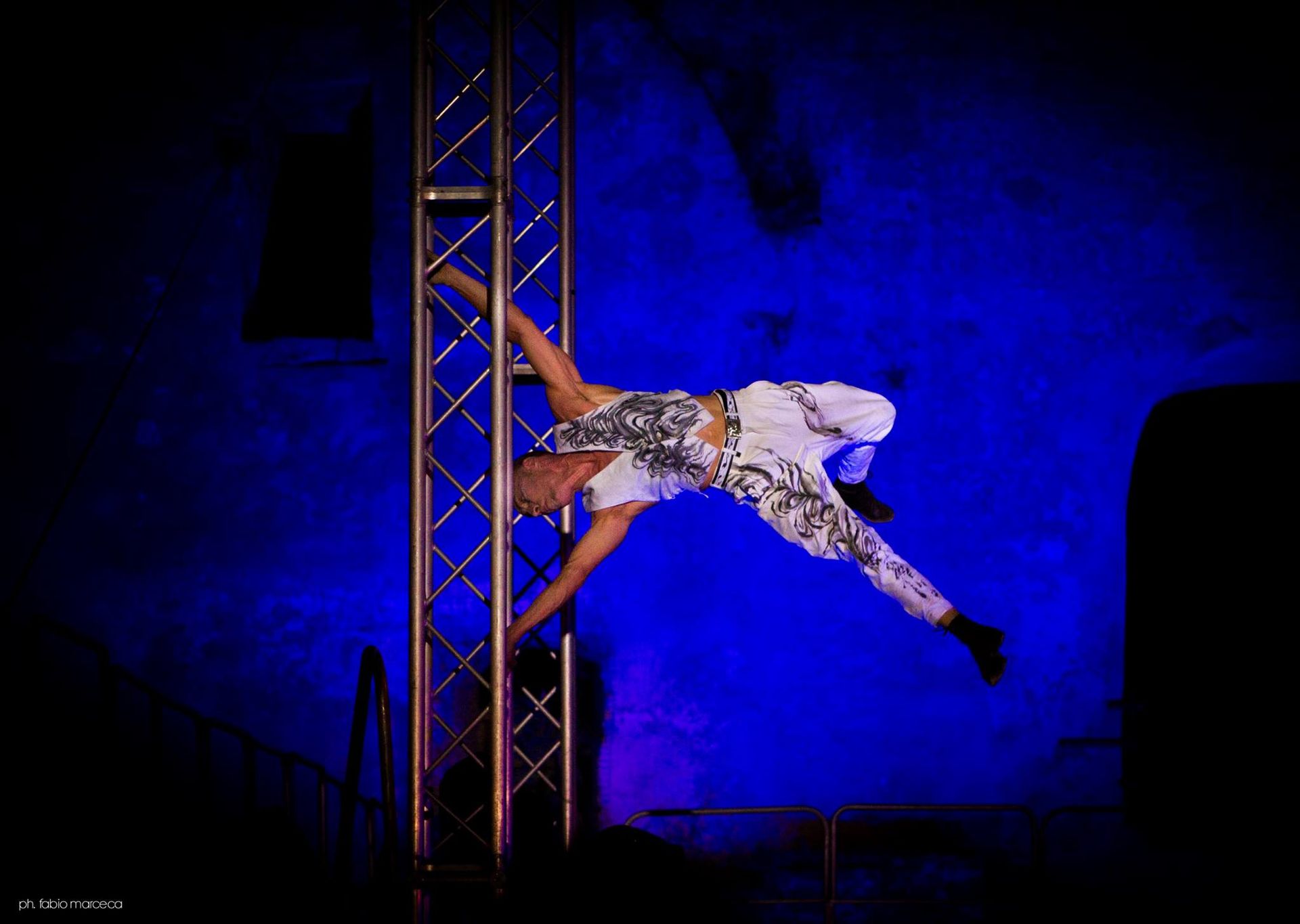 Una donna sta facendo la verticale su un palo davanti a una luce blu.