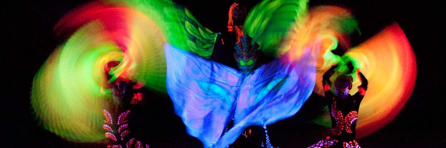 Un gruppo di persone sta ballando in una stanza buia con luci fosforescenti.