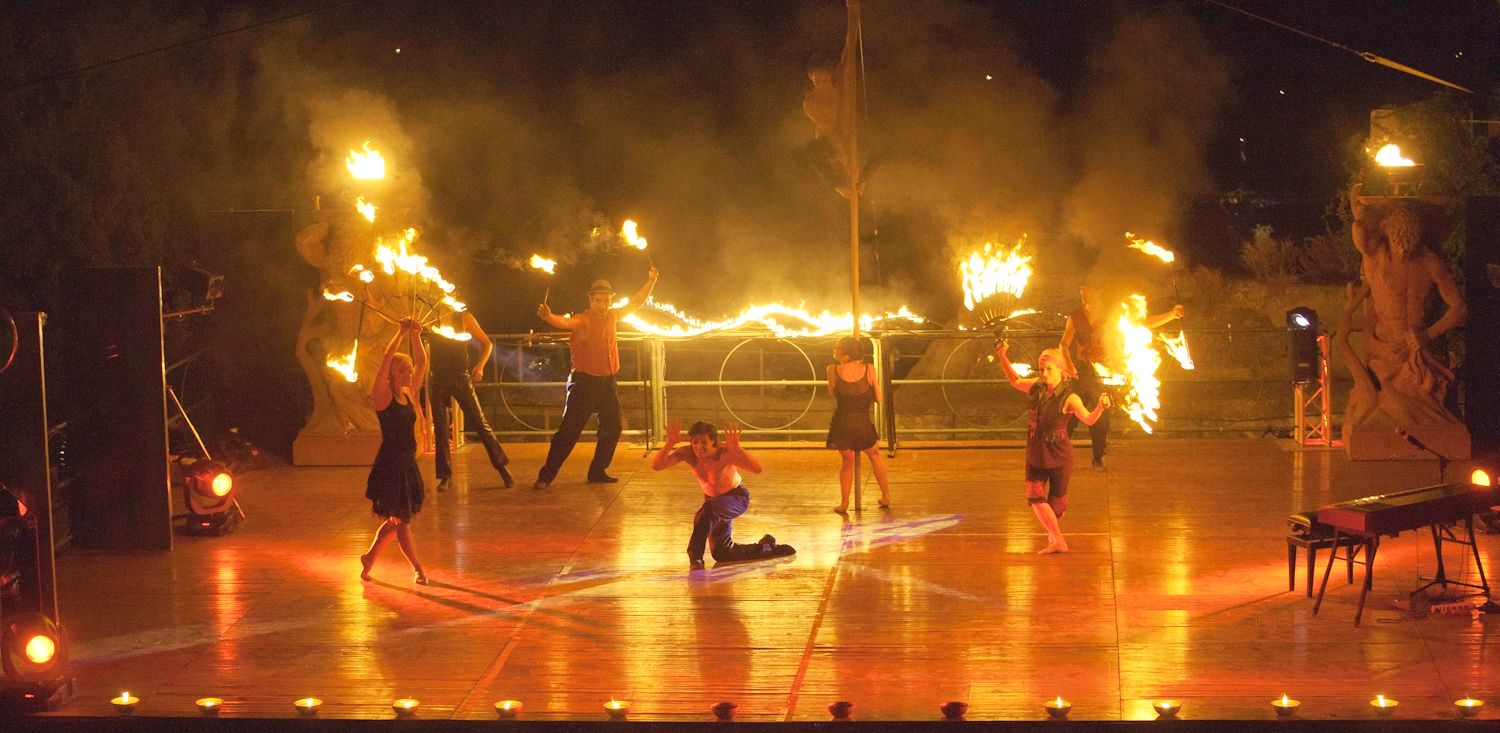 Un gruppo di persone sta ballando su un palco con il fuoco in mano.