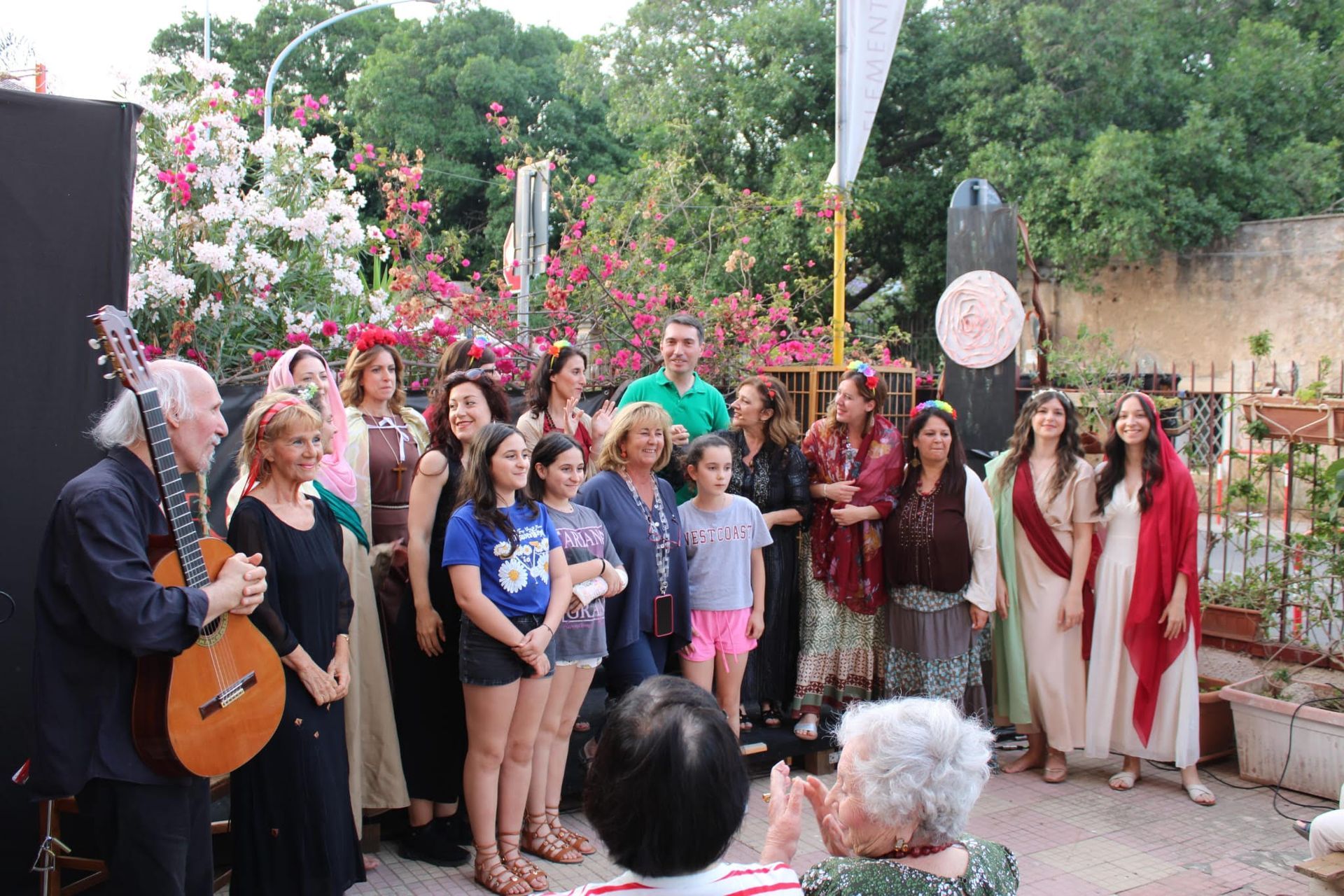 Un gruppo di persone è in piedi attorno a un uomo che suona una chitarra.