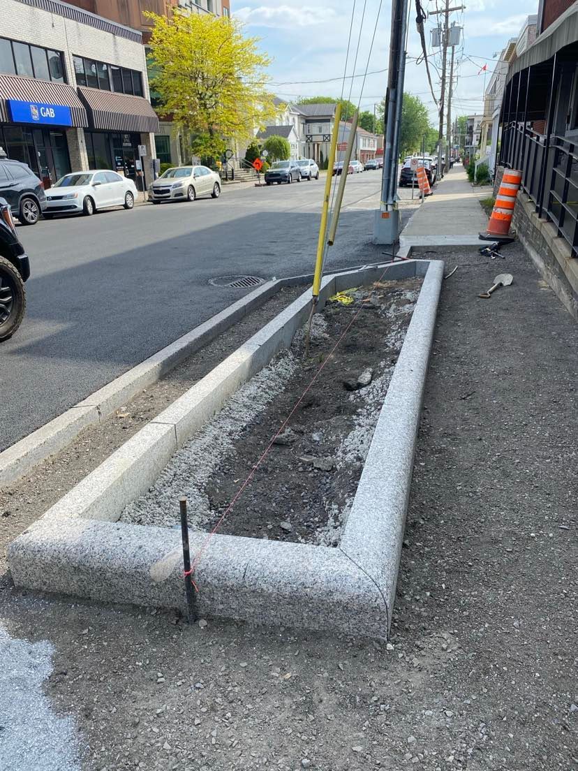 Une bordure en béton est en cours d'installation sur le côté d'une rue.