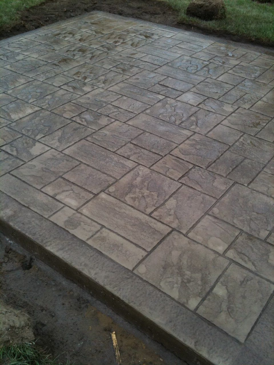 Un patio en béton avec un motif de briques est en cours de construction dans une cour.