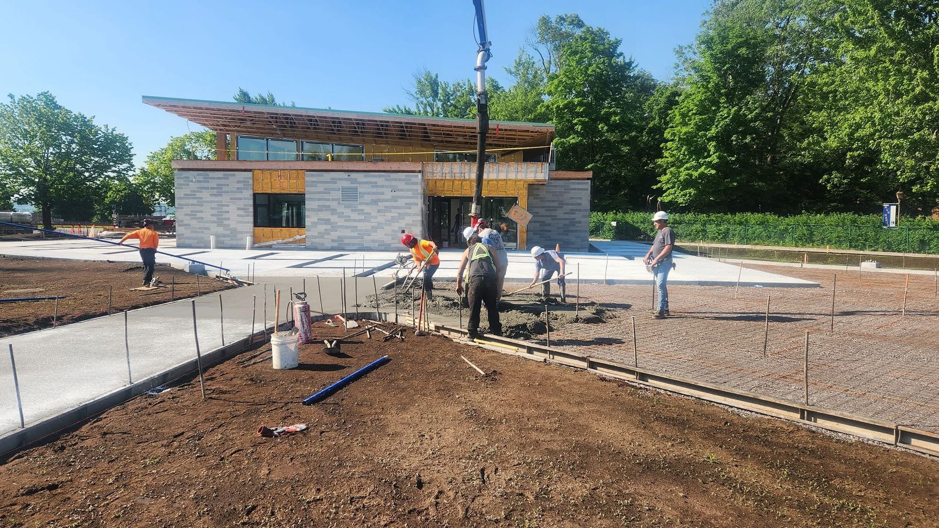 Un groupe d'ouvriers du bâtiment travaille sur une allée en béton devant un bâtiment.