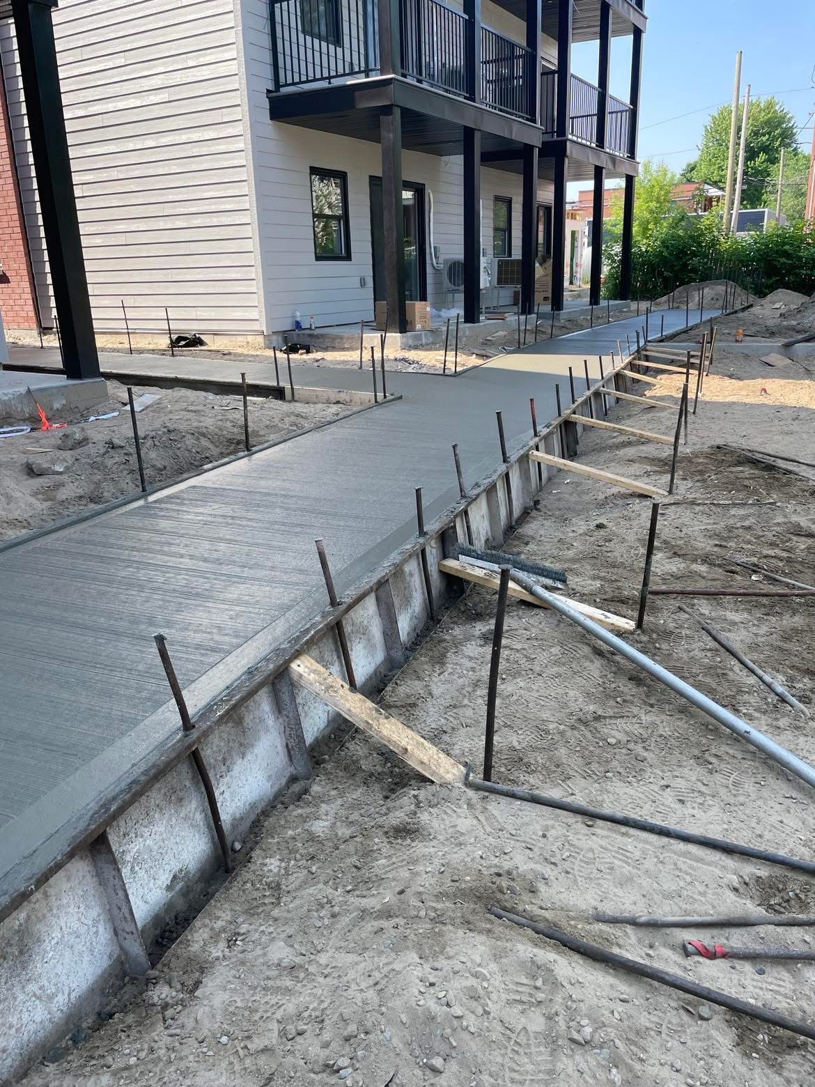 Une passerelle en béton est en cours de construction devant une maison.