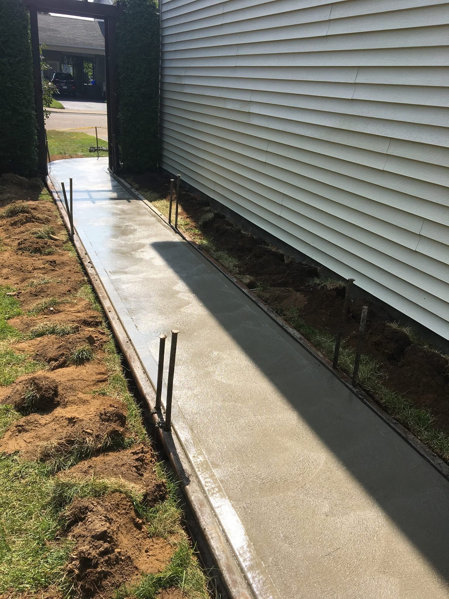 Une passerelle en béton est en cours de construction à côté d'une maison.