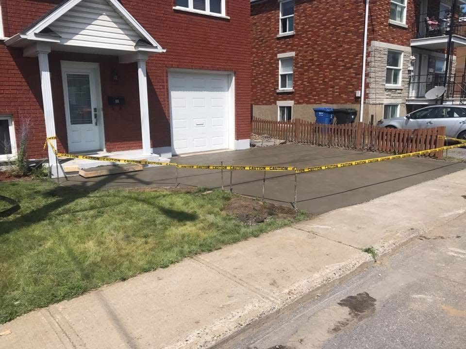 Une maison en briques avec une allée en béton devant elle.