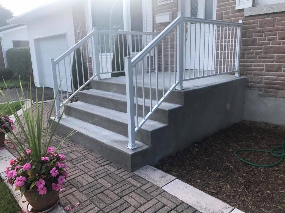 Une allée en briques avec des escaliers et une balustrade devant une maison.