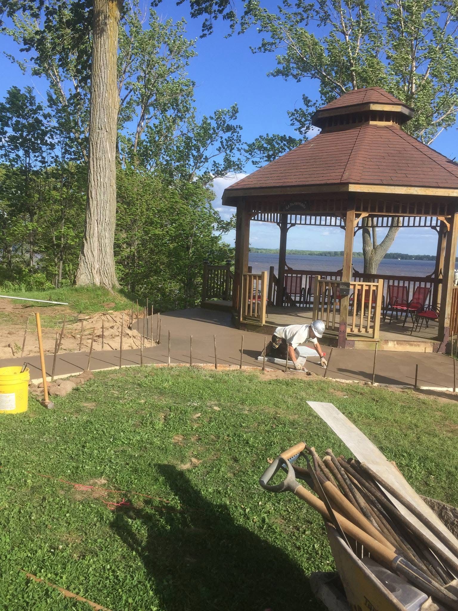 Un homme travaille sur un belvédère dans une cour arrière.