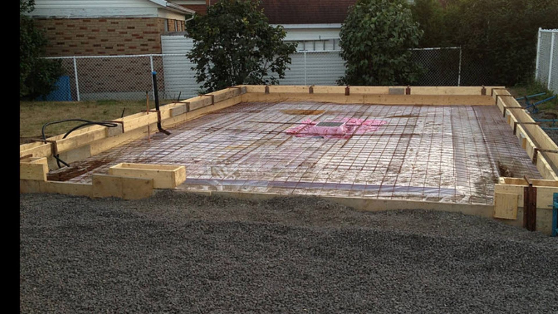 Une fondation en béton est en cours de construction dans une cour arrière.