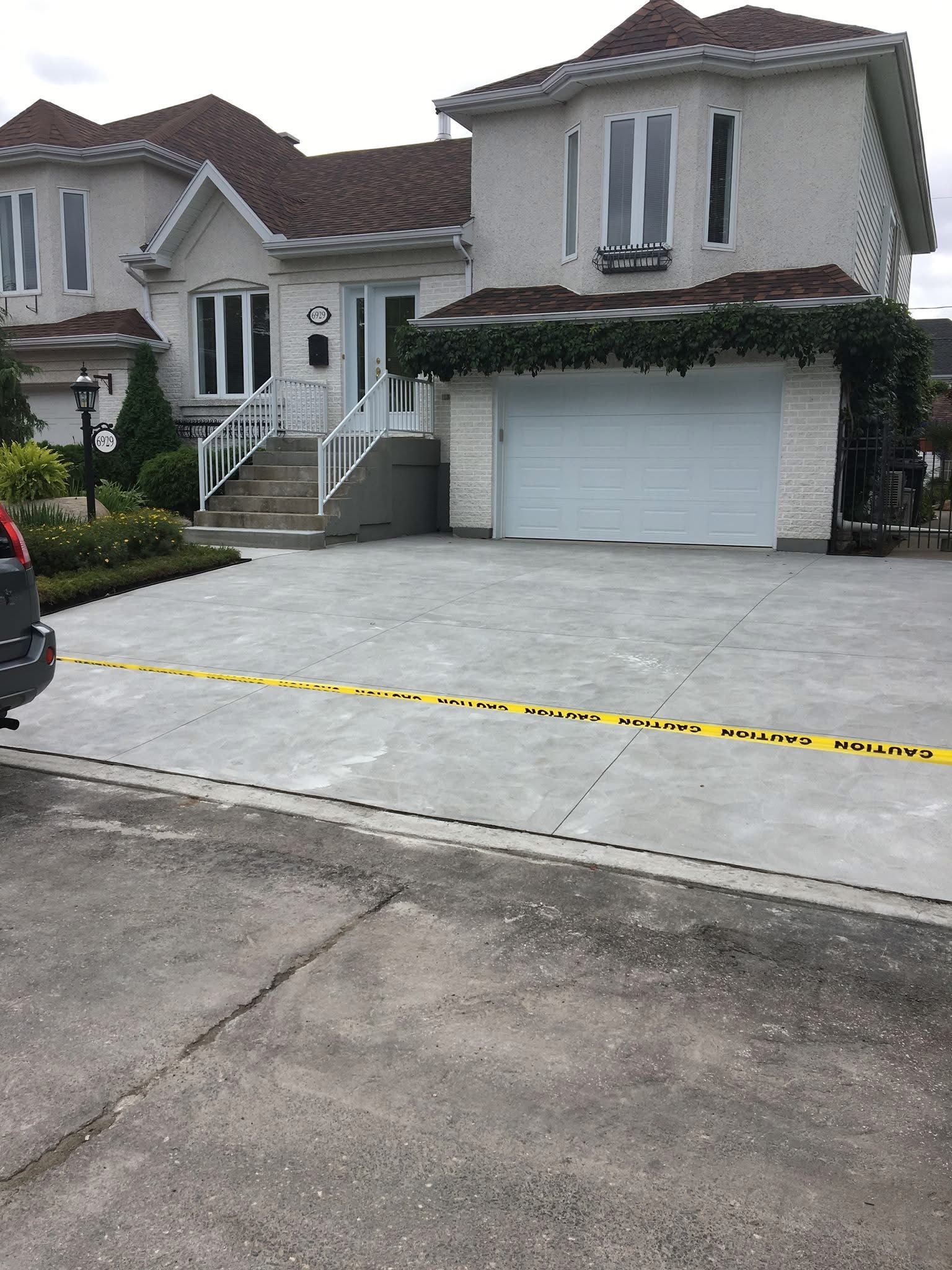 Une voiture est garée devant une grande maison avec une allée en béton.