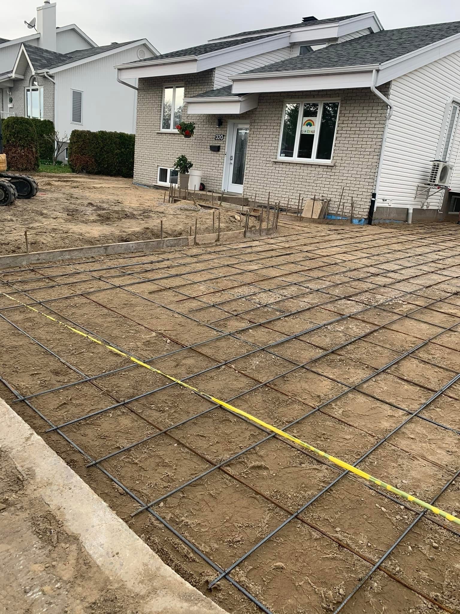 Une allée en béton est en cours de construction devant une maison.
