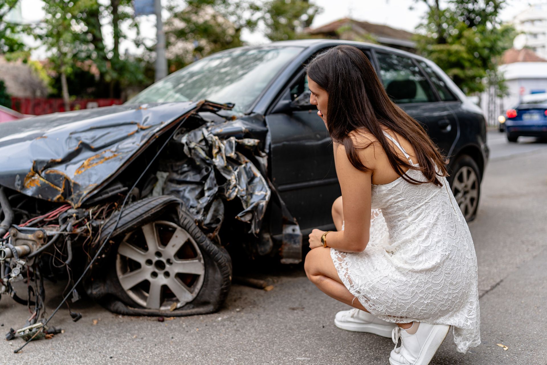 A woman stands beside her crashed car.