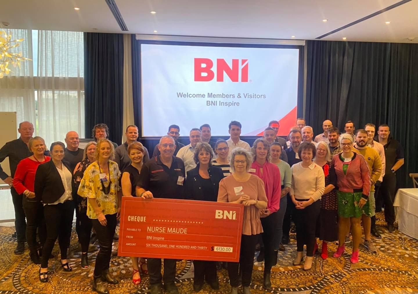 A group of people standing in front of a screen that says bni