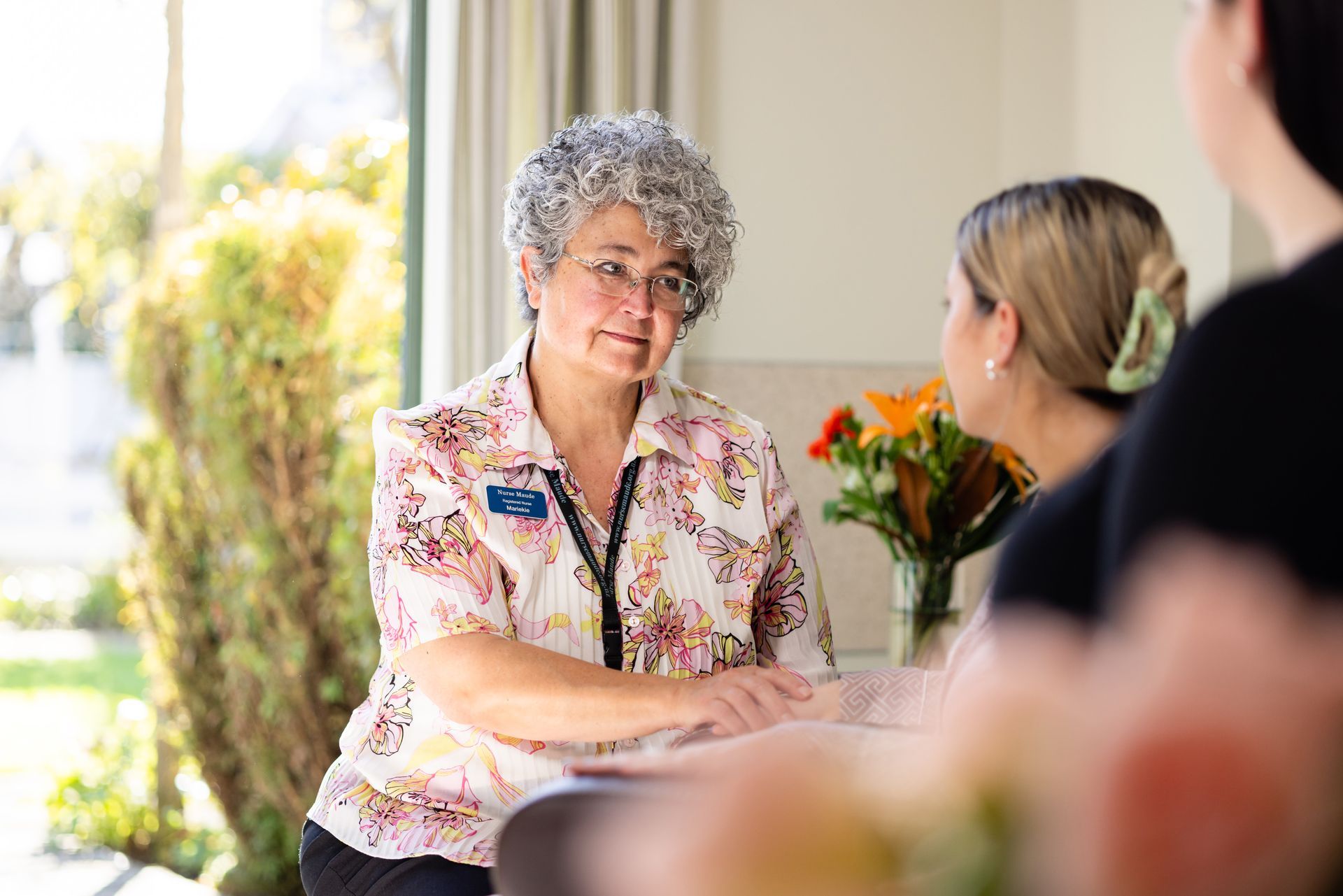 A woman is sitting at a table talking to two other women.