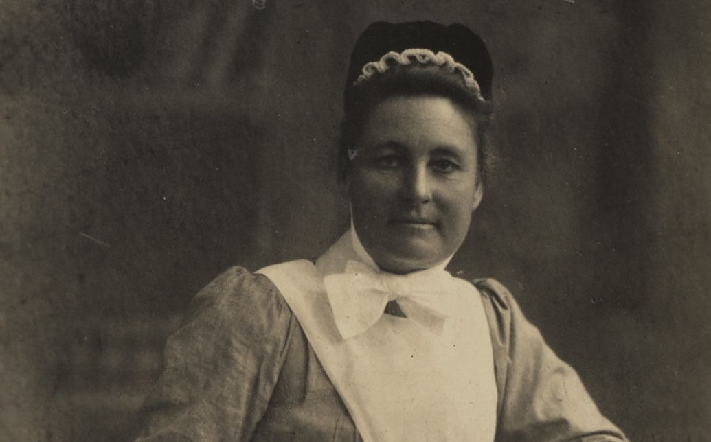 A black and white photo of a woman in a white apron - Nurse Maude