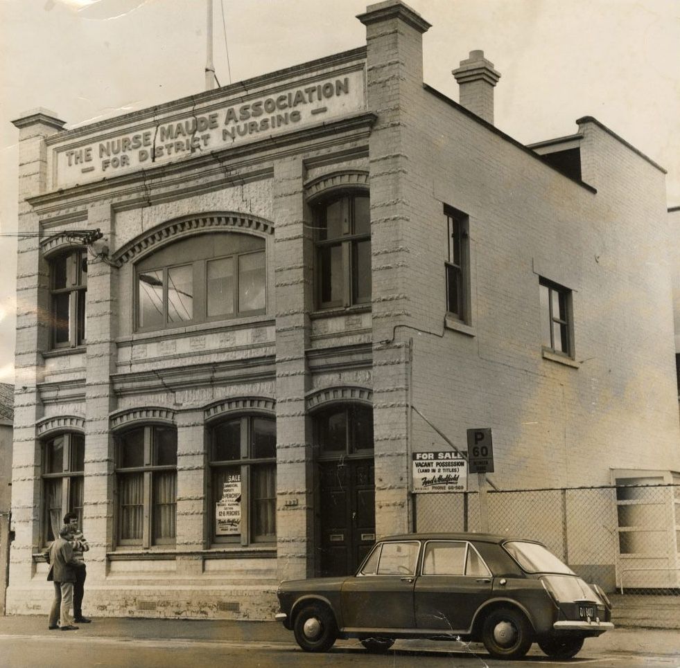 A car is parked in front of a building that says nurses association - Nurse Maude