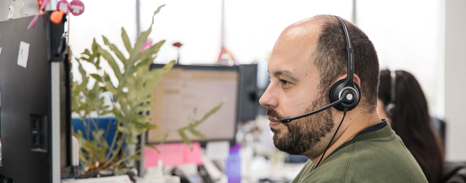 A man wearing a headset is sitting in front of a computer.