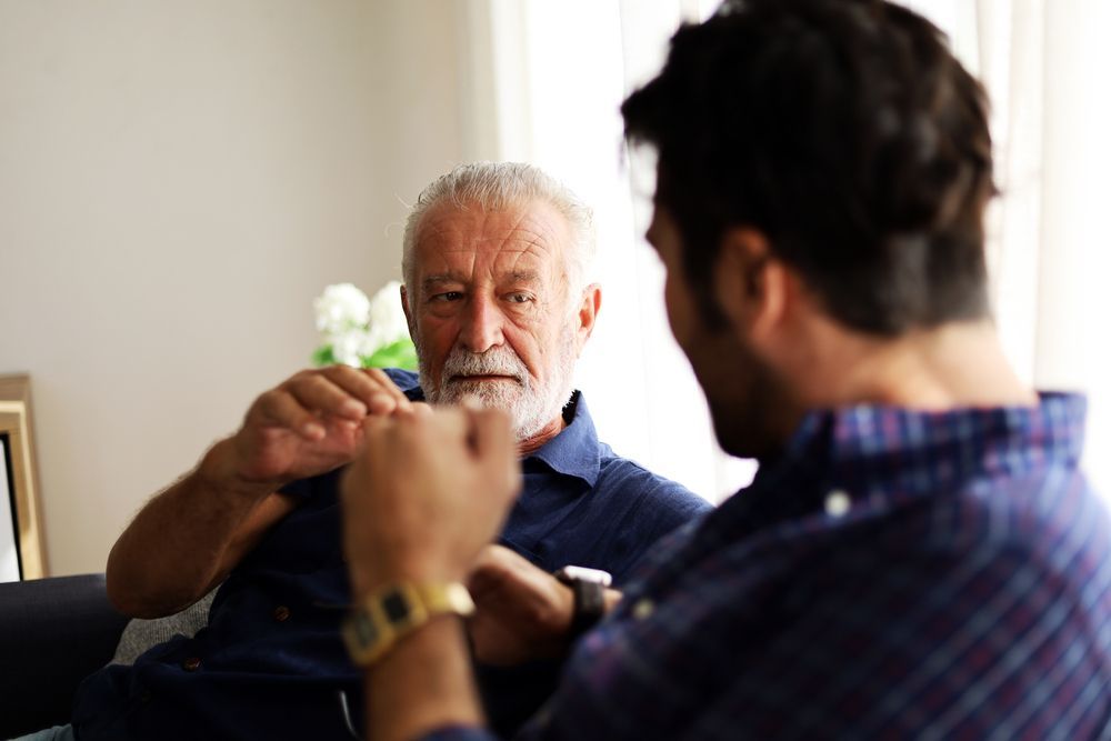 Two men are sitting on a couch talking to each other