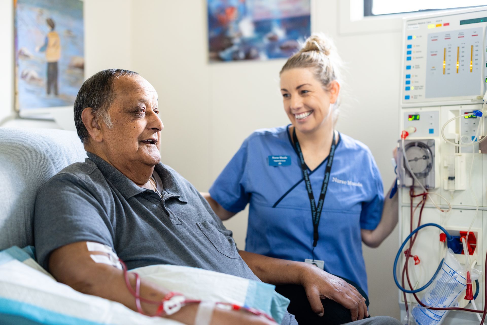 A nurse is talking to an elderly man in a hospital bed