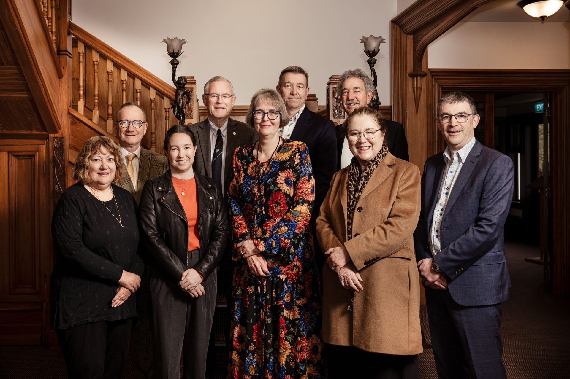 A group of people posing for a picture in front of a wooden staircase