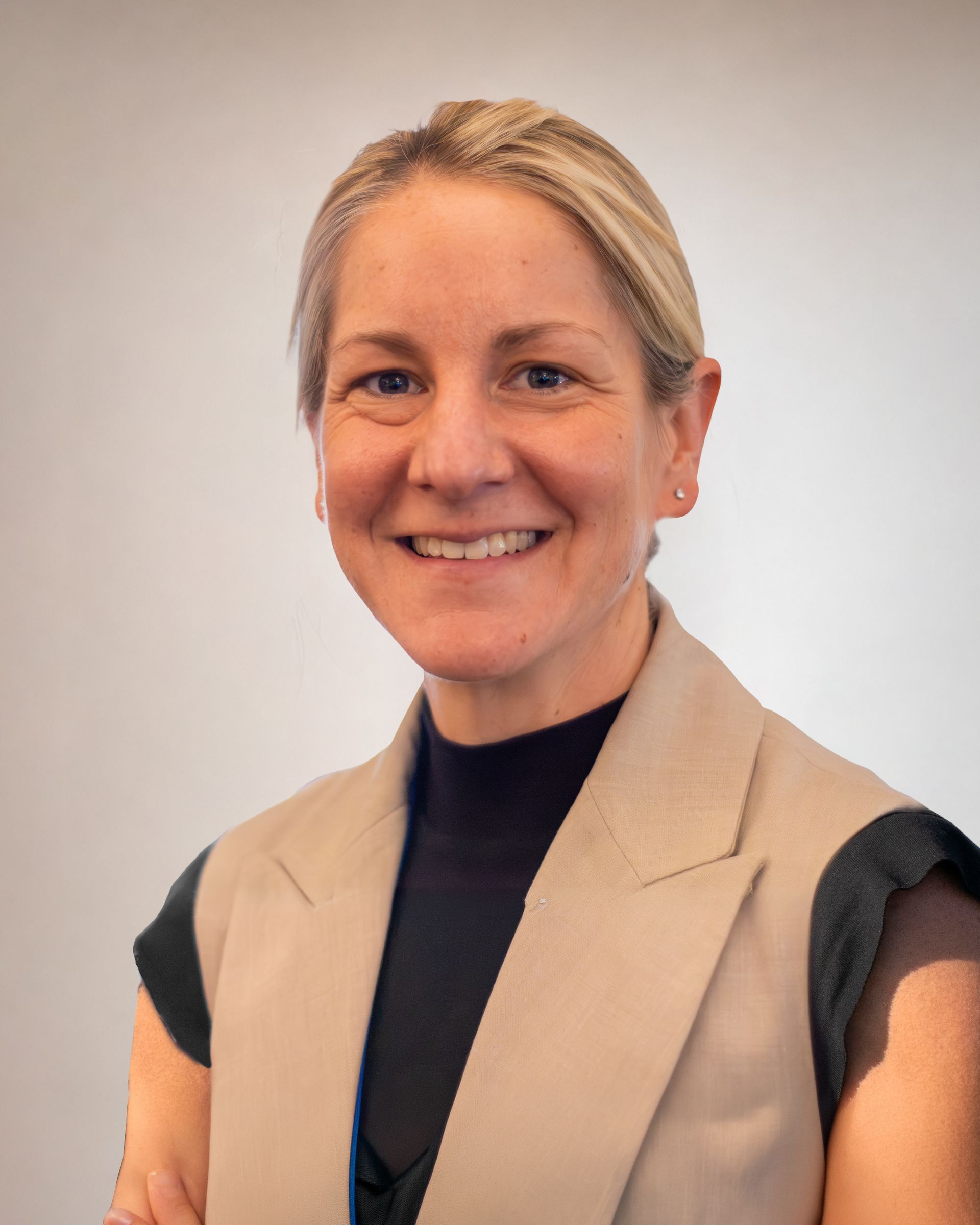 Rowhan Kelly, GM Service Development Smiling woman in a beige vest and black top against a plain light background